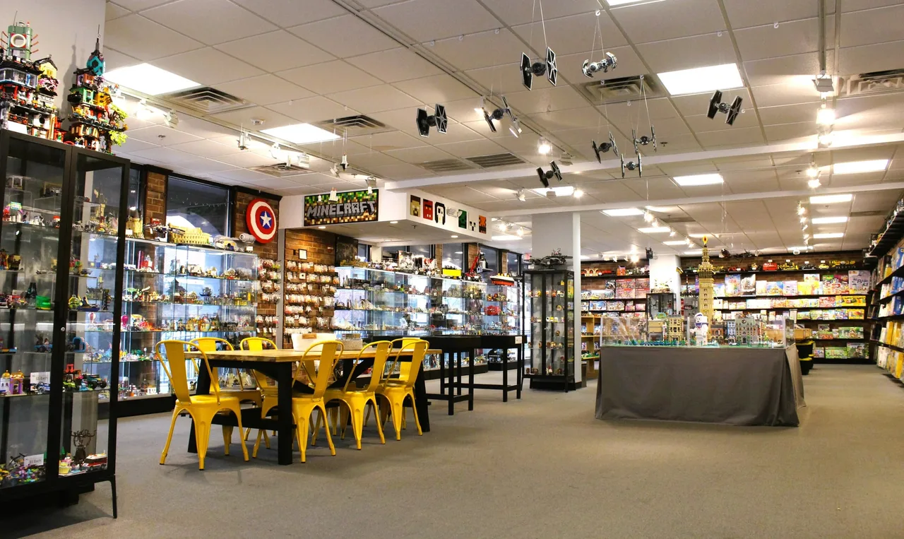 Interior of The Minifig Shop with display cases, build tables, and hanging models